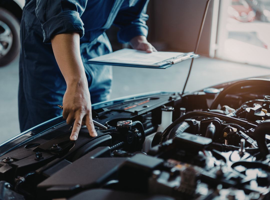 ASE-certified mechanic inspecting a vehicle engine bay with clipboard during a diagnostic check at a Sarasota auto repair shop