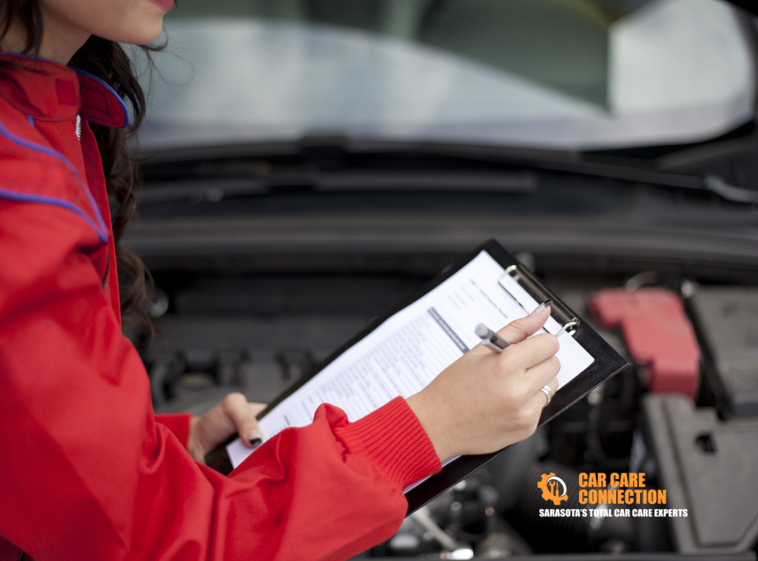 vehicle inspection Sarasota automotive technician drawing up a multi-point vehicle inspection checklist with engine bay open at Car Care Connection Sarasota