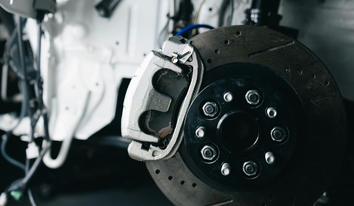 Close-up of a drilled and slotted brake rotor with caliper and brake pads visible during a brake inspection near Siesta Key